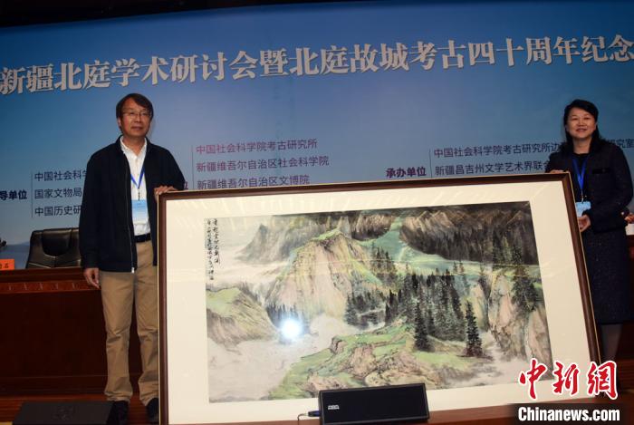 开幕式上，陈星灿(左)代表中国社会科学院考古研究所接受新疆昌吉州赠送的绘画作品?！∷镒苑?摄